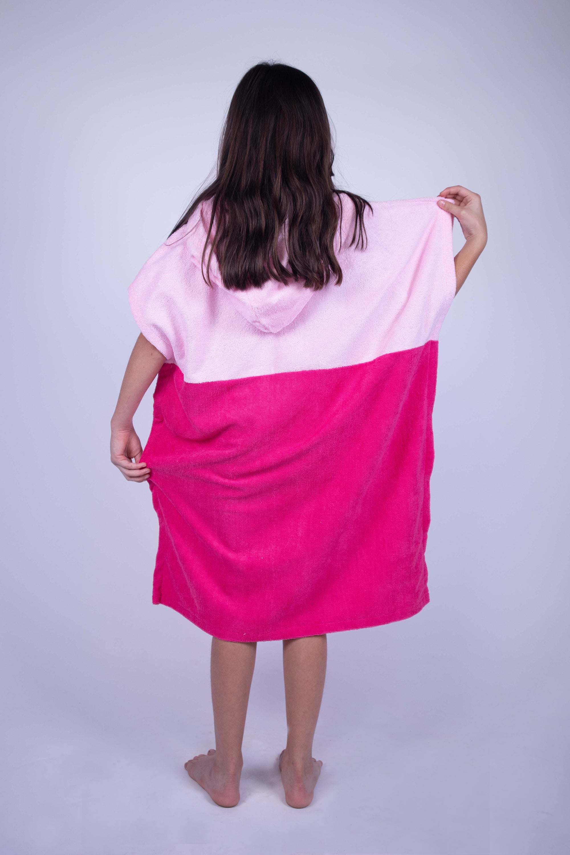 Poncho toalla cambiador de dos colores (Baby pink y rosa mexicano), con bolso en frente y gorro. Ideal para cambiarte en cualquier lugar cómodamente y estar en el después del agua. Para niños y niñas.