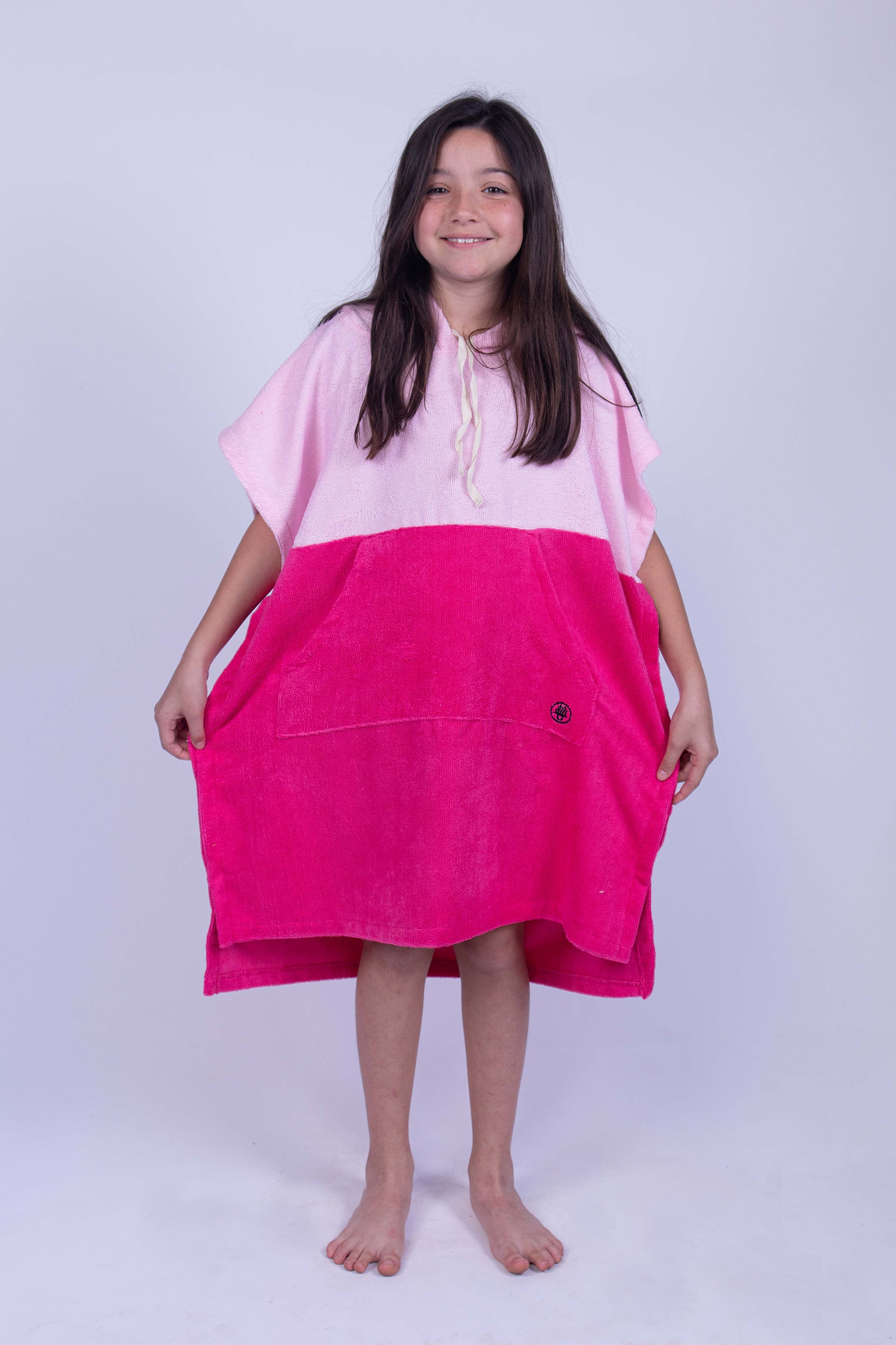 Poncho toalla cambiador de dos colores (Baby pink y rosa mexicano), con bolso en frente y gorro. Ideal para cambiarte en cualquier lugar cómodamente y estar en el después del agua. Para niños y niñas.